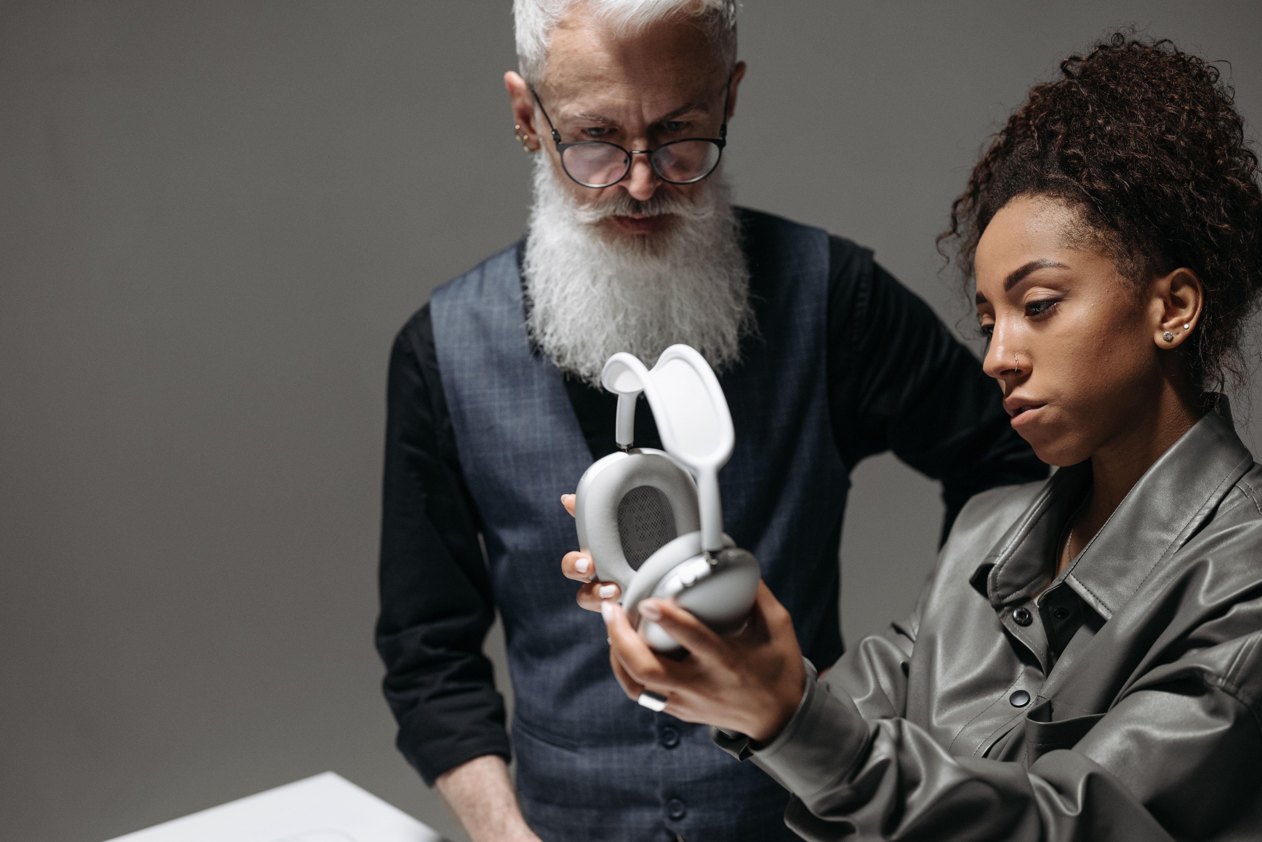 Two people analyzing and reviewing wireless headphones in a corporate setting