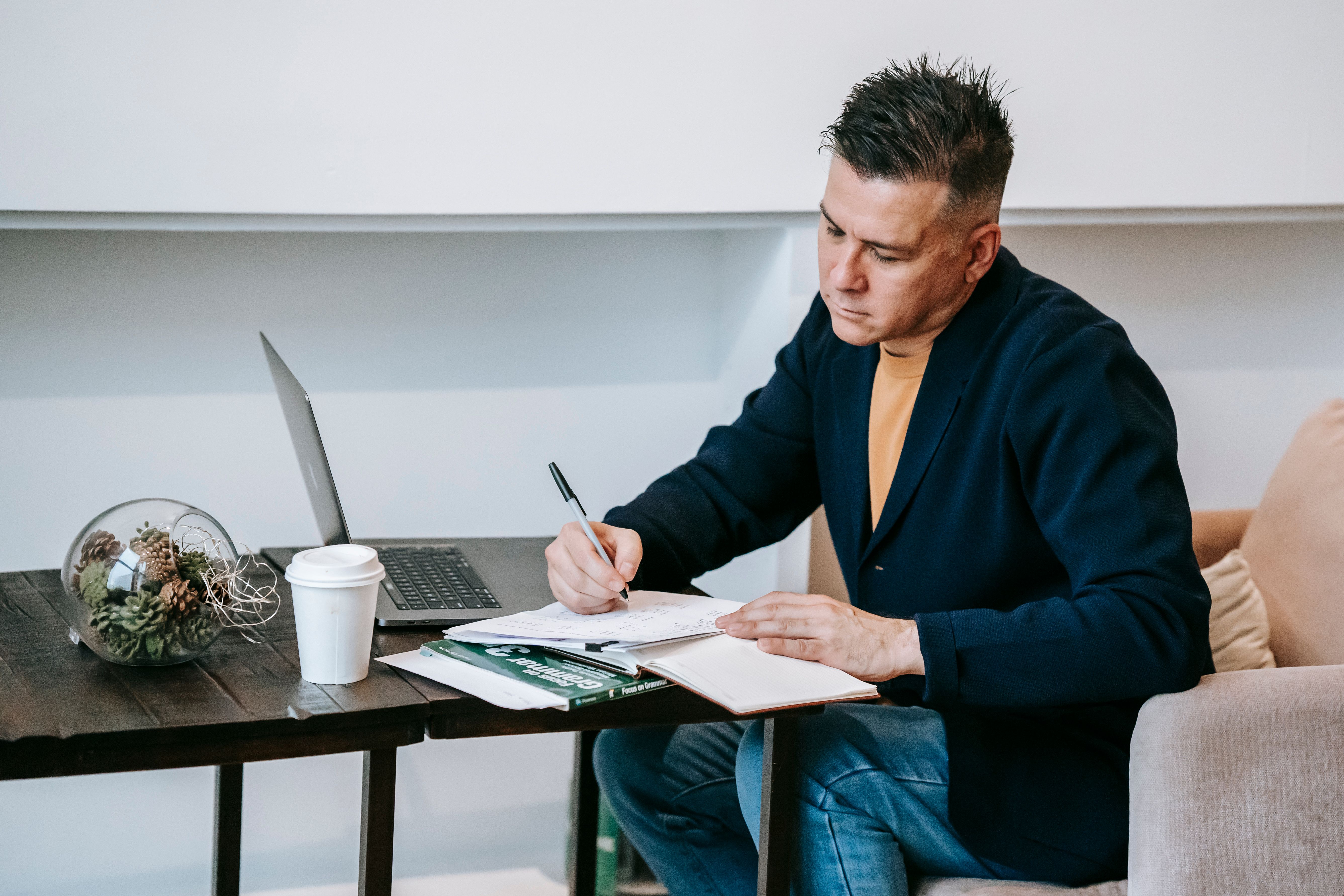 Tech reviewer writing product review notes in a home office with a laptop